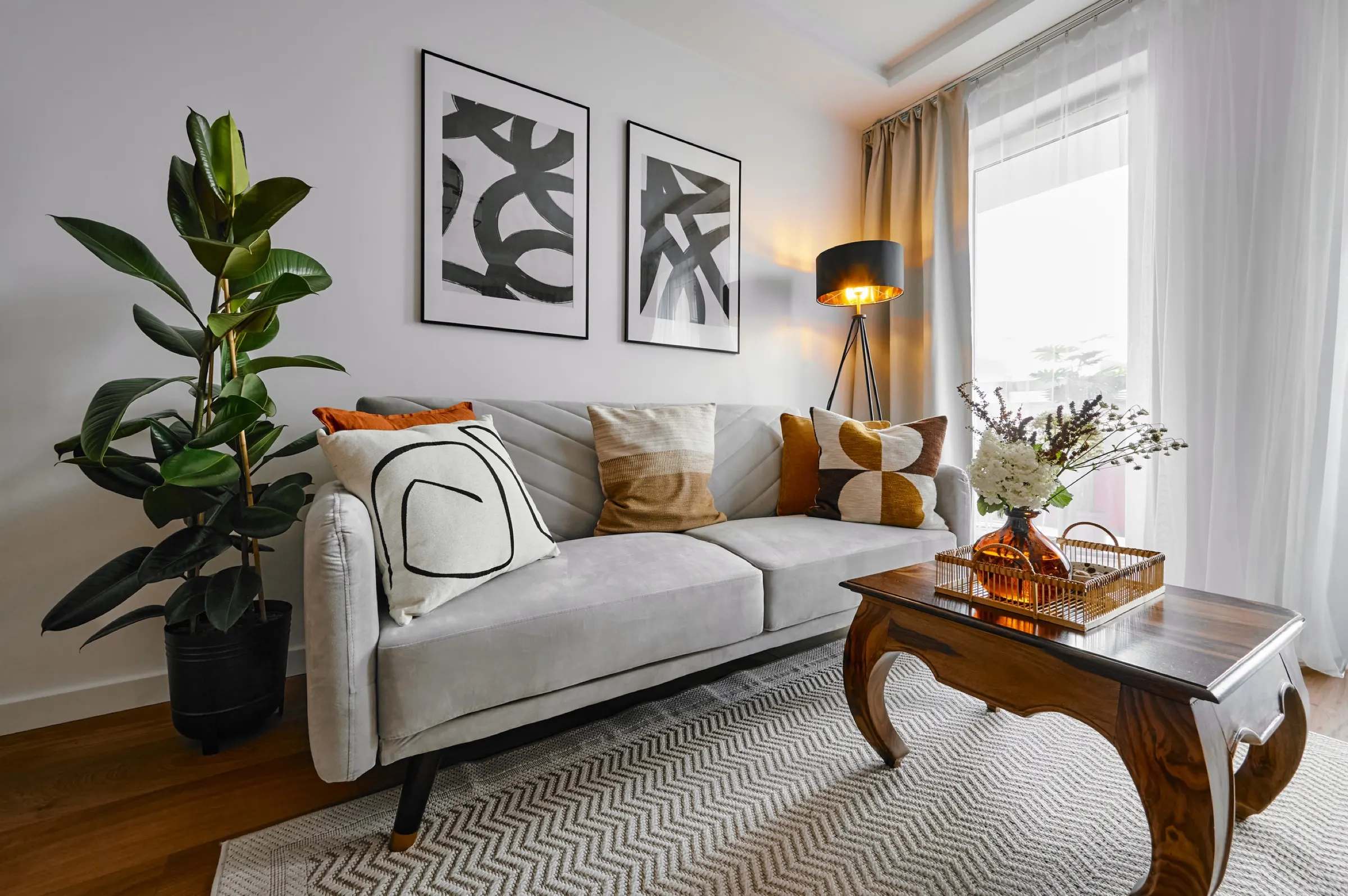 Living room with a light sofa, carved coffee table and a fig plant