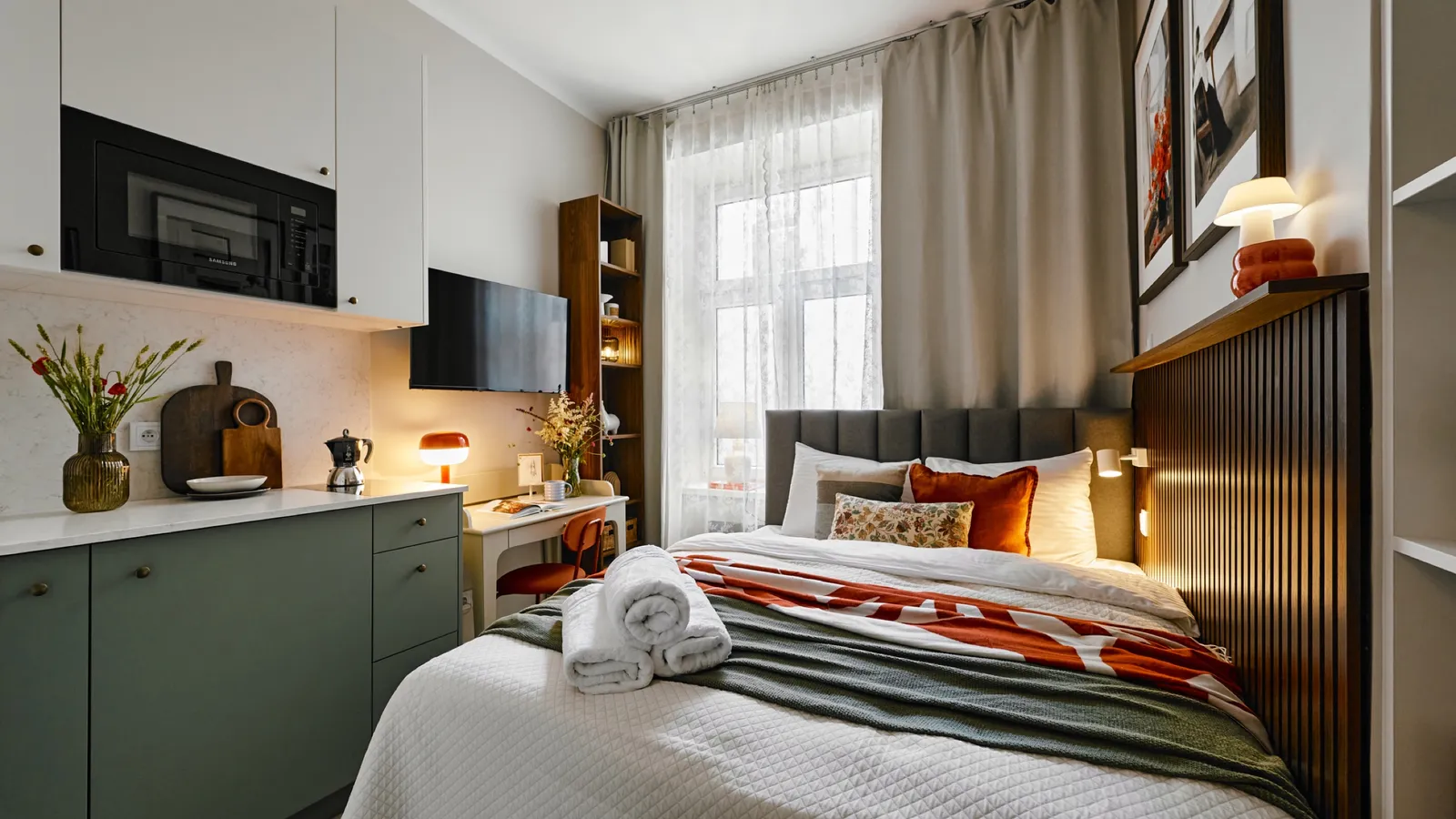 Studio with the bed, kitchenette and a lace-curtained window
