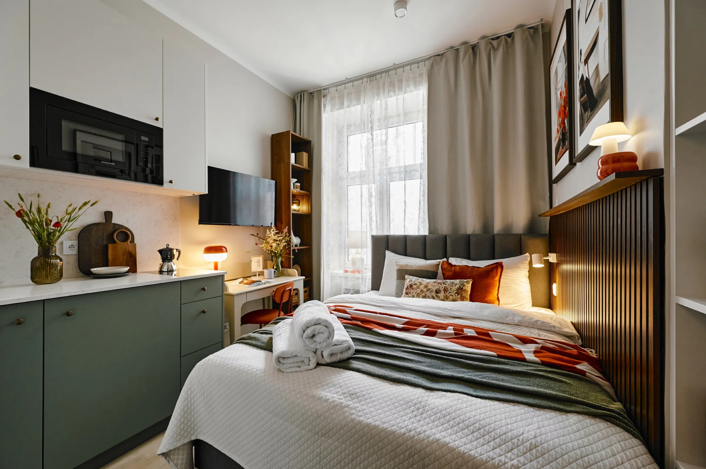 Studio with the bed, kitchenette and a lace-curtained window