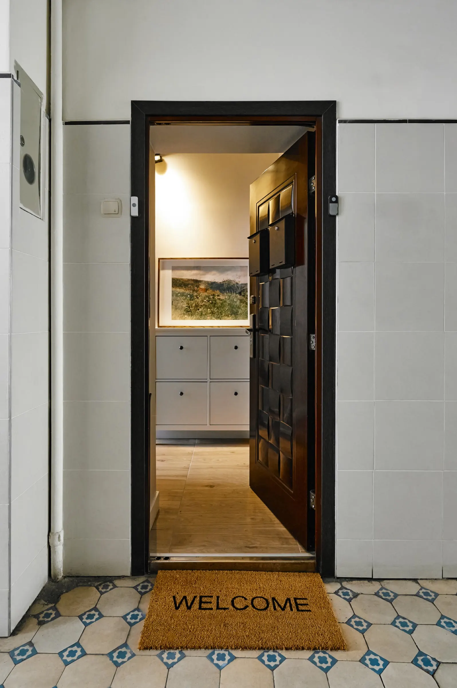 Entrance from the hallway to the shared corridor, with a welcome mat